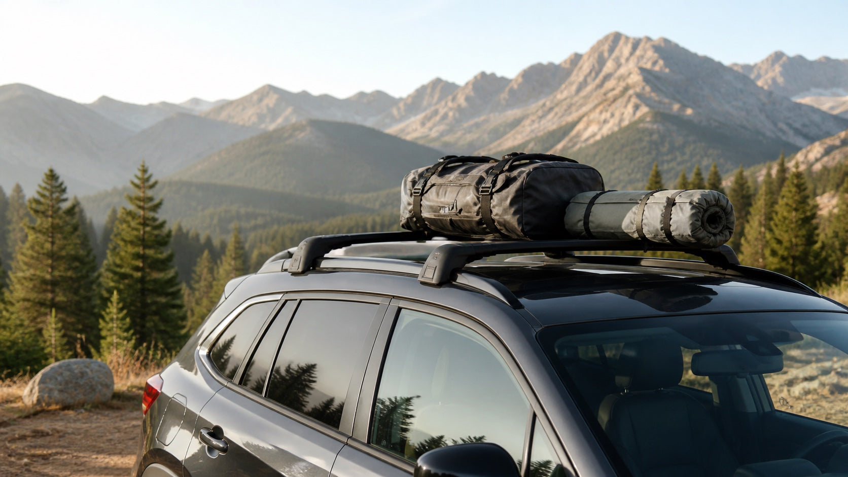Roof rack crossbars carrying camping gear on an SUV at a mountain trailhead